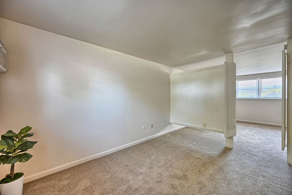 a living room with white walls and carpet and a window