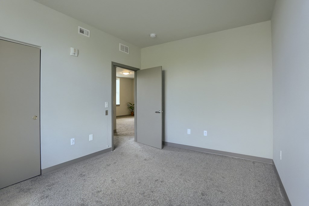 Mount Joy Senior Housing | a bedroom with a carpeted floor and a door that leads to a hallway
