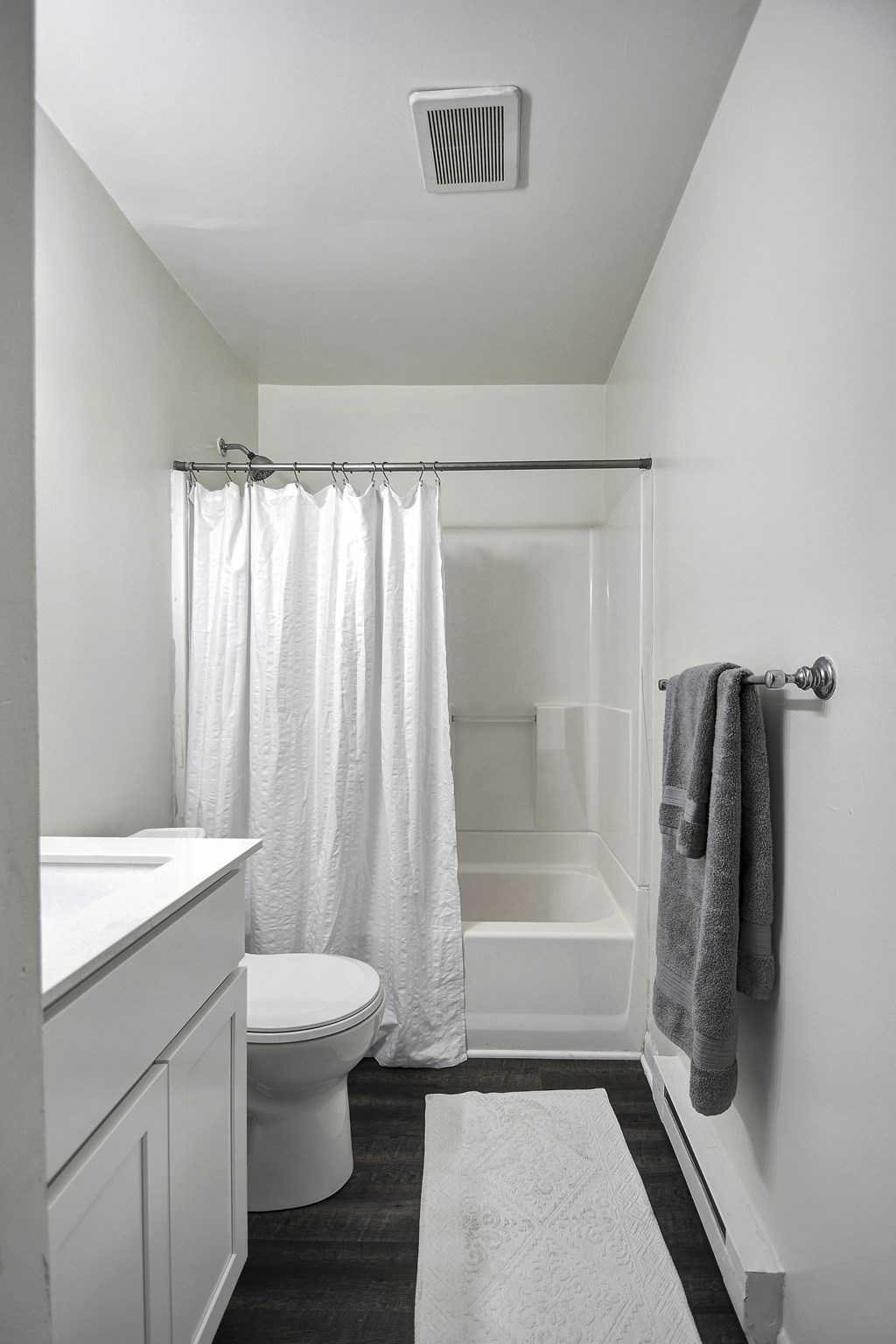 A white bathroom with a toilet, sink, and shower.
