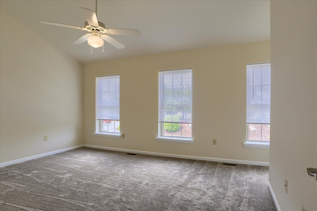 A room with a ceiling fan and carpeted floor.