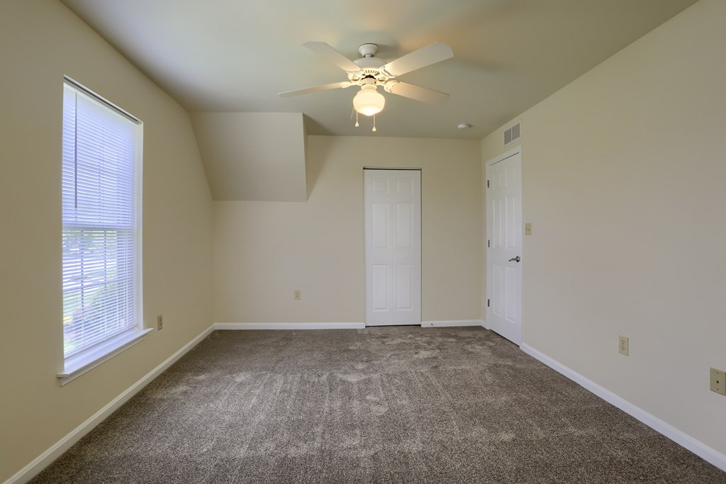 A room with a ceiling fan and carpeted floor.