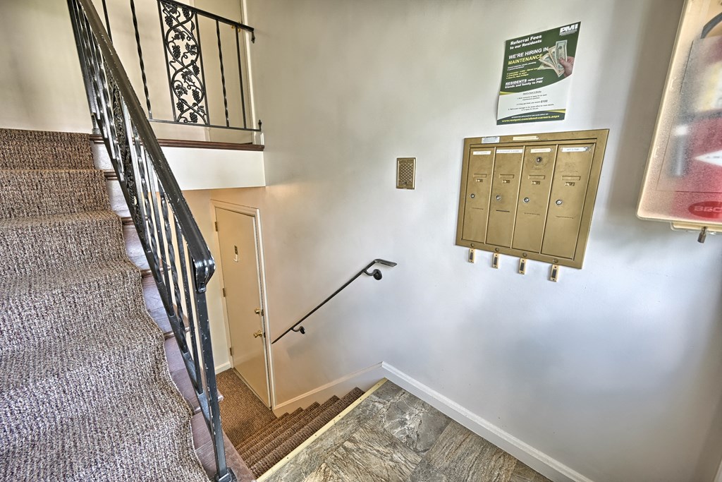a stairwell with two mailboxes on the wall and a staircase with a railing