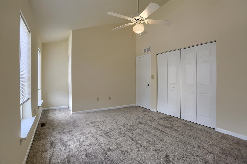 A room with a ceiling fan and carpeted floor.