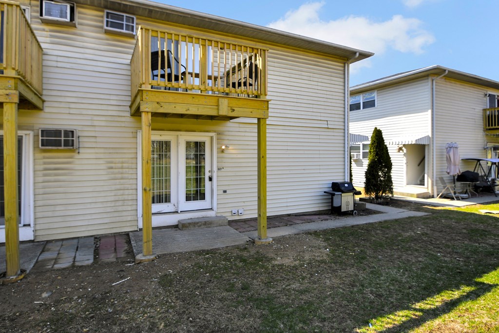 A house with a balcony and a small tree in the front yard.