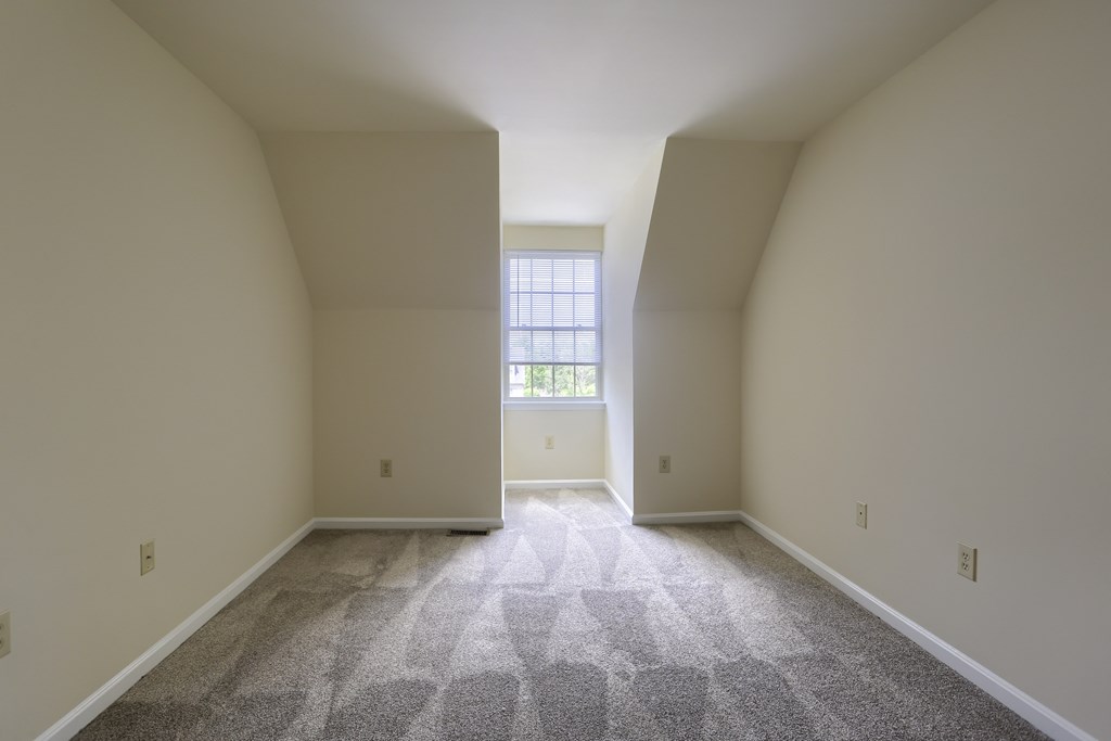A room with a carpeted floor and a window.