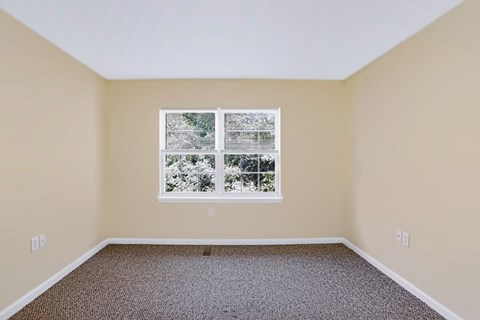 A room with a window showing trees outside.