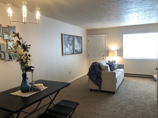 A living room with a couch, a table, and a vase of flowers.