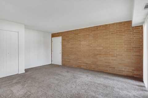 a bedroom with a brick wall and a carpeted floor