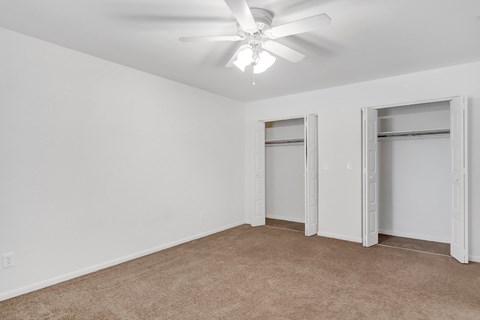 a bedroom with a ceiling fan and two closets