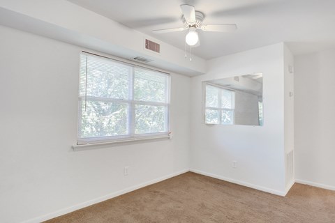 an empty room with a window and a ceiling fan