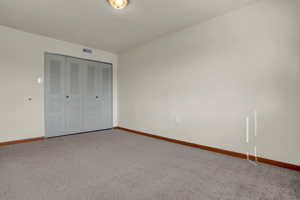 a bedroom with white walls and carpet and a closet