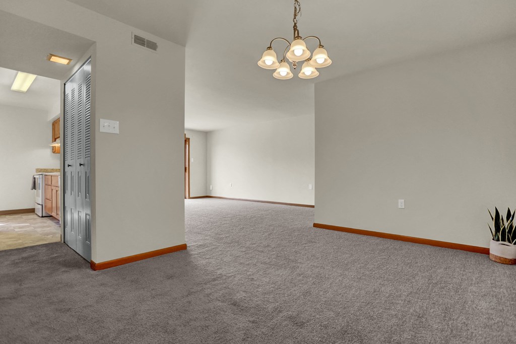 a living room with carpet and a door to a kitchen