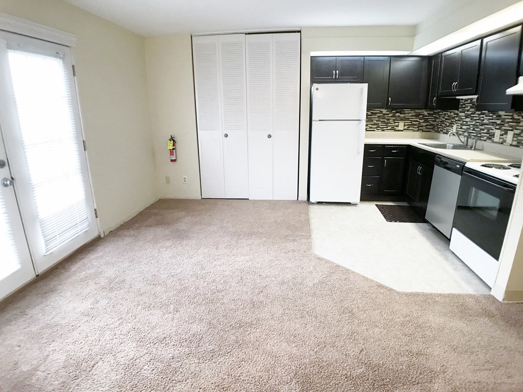an empty kitchen with black cabinets and a white refrigerator