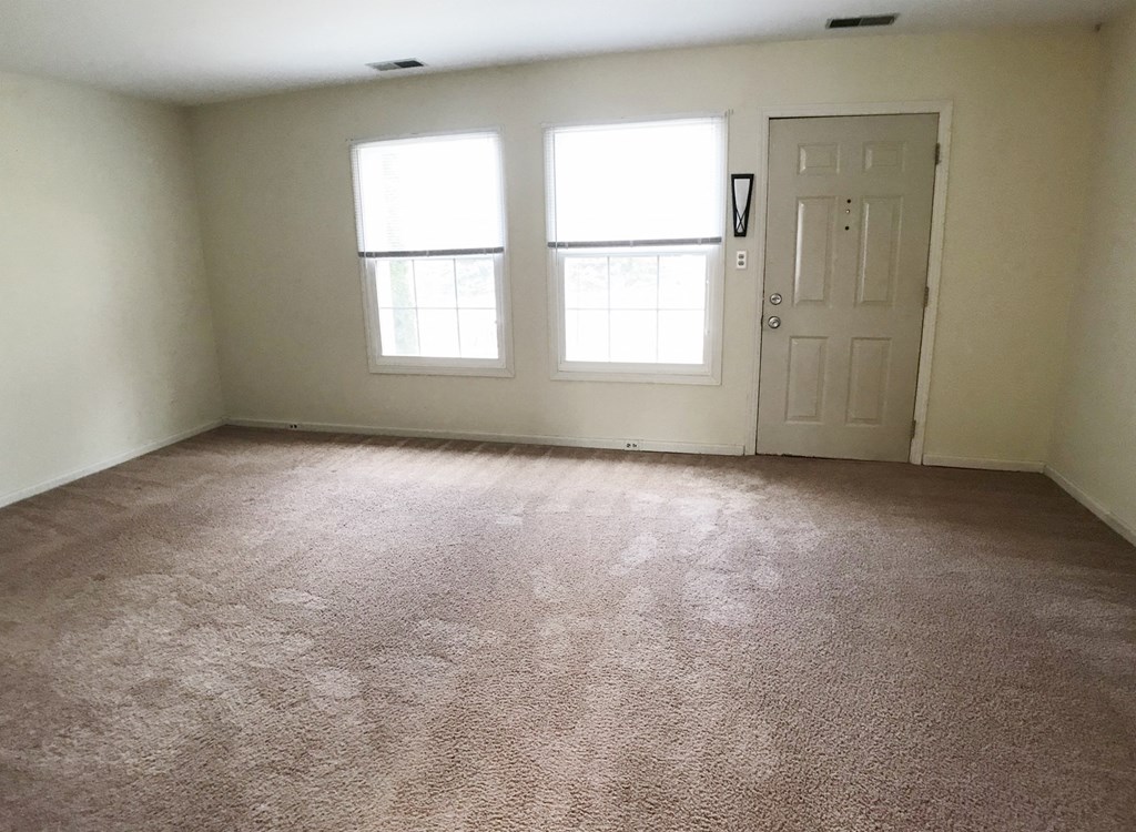 an empty room with a door and two windows