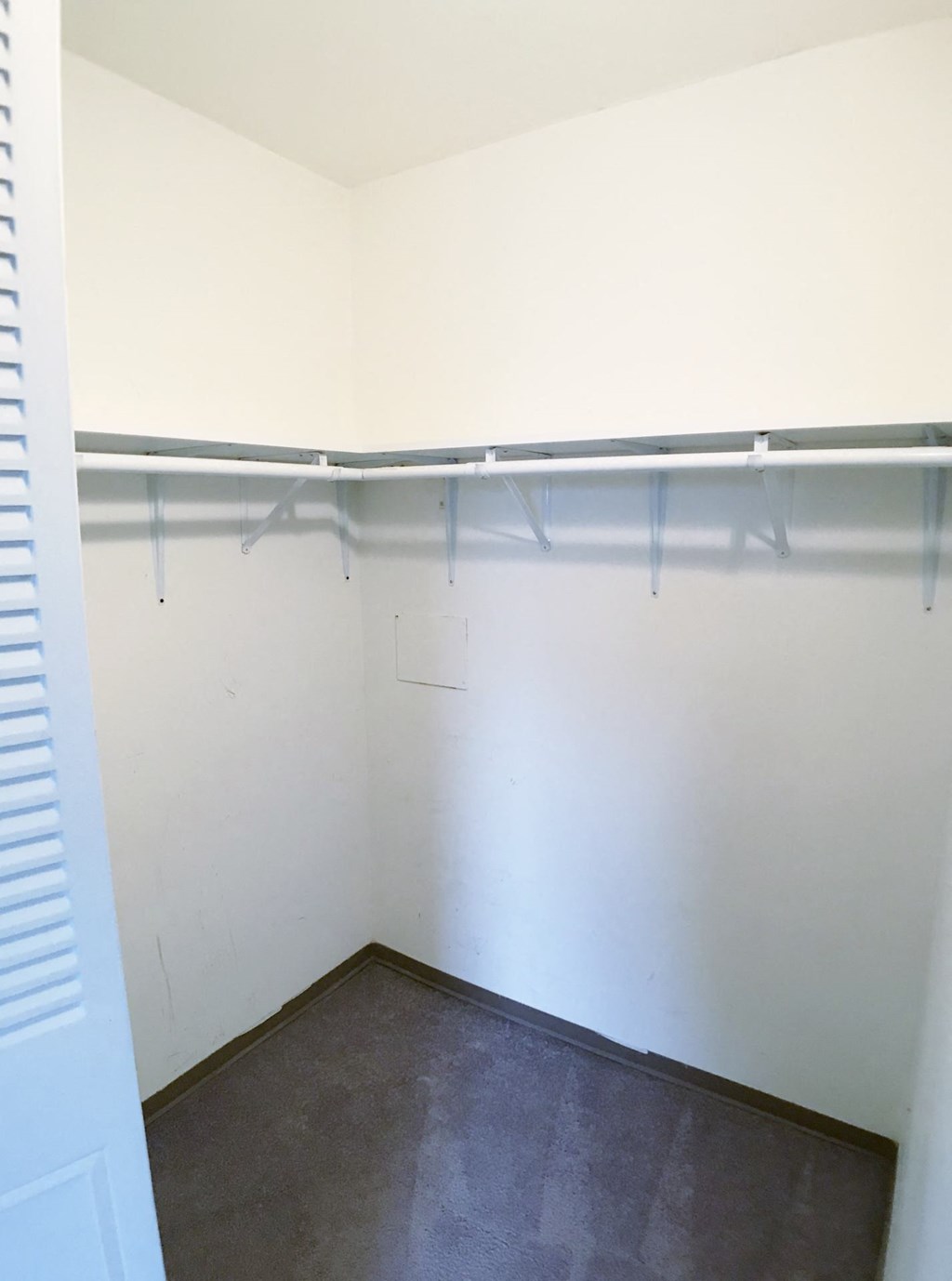a empty closet with a hanging rail on the wall
