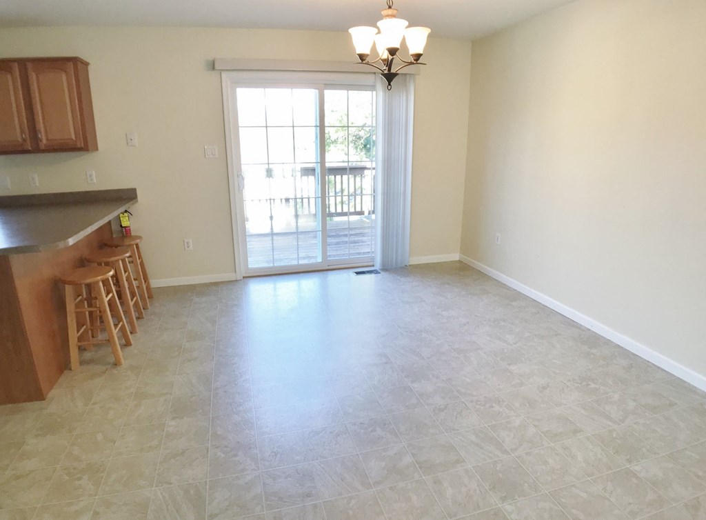 an empty living room with a kitchen and a sliding glass door