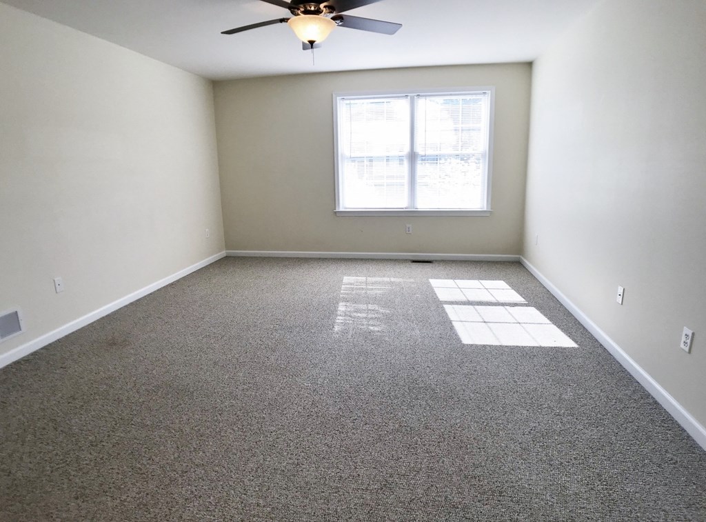 an empty room with a ceiling fan and a window
