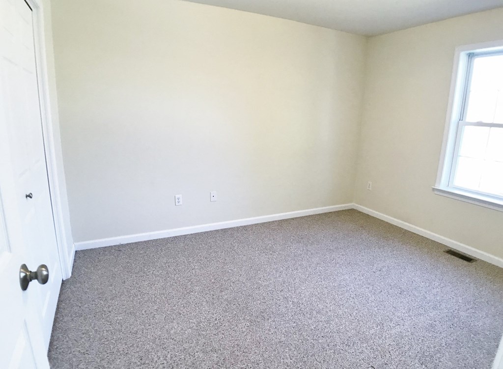 an empty room with carpet and two windows