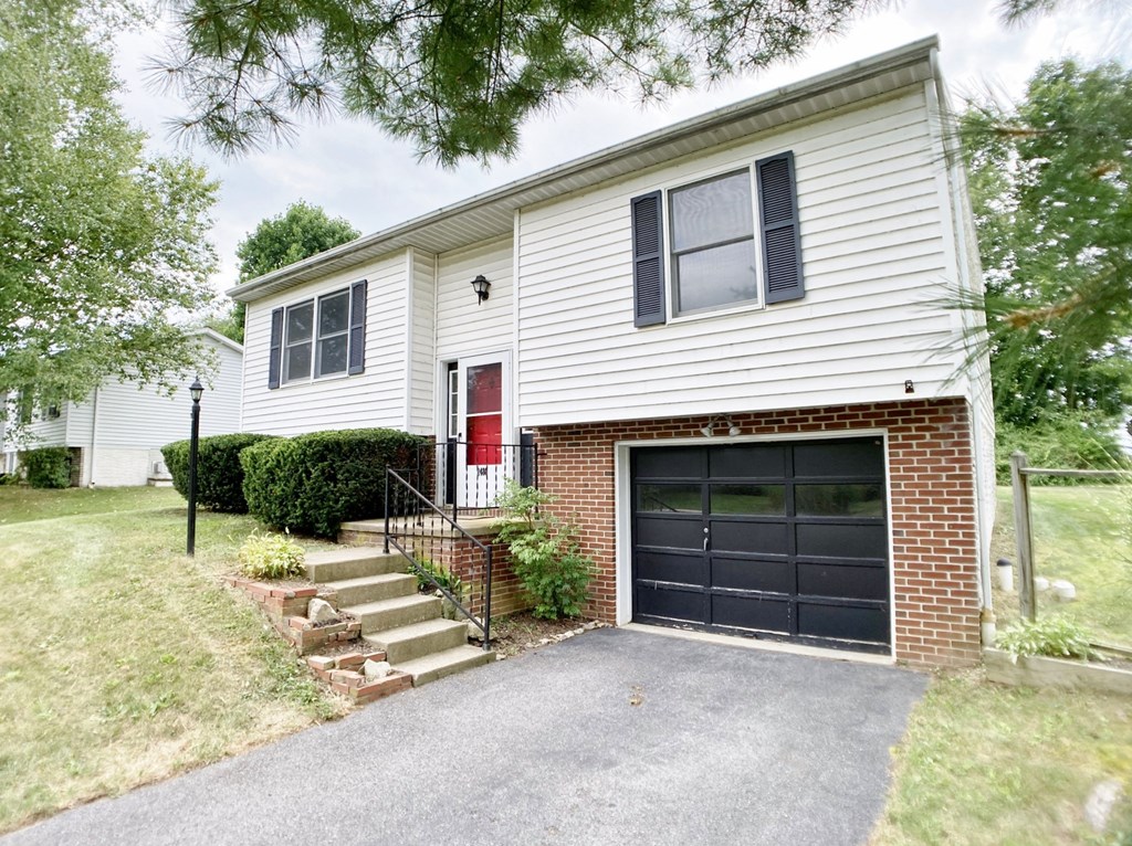 the front of a white house with a black garage door