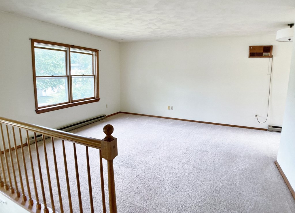 an empty living room with a staircase and a window