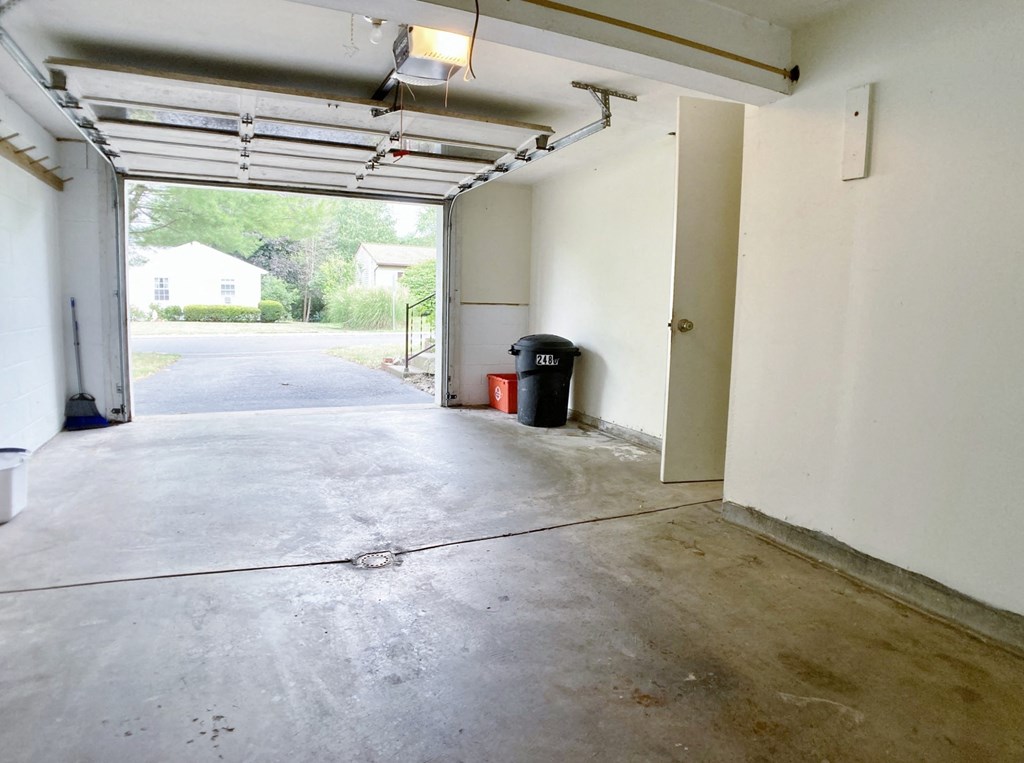 an empty garage with white walls and a garage door open