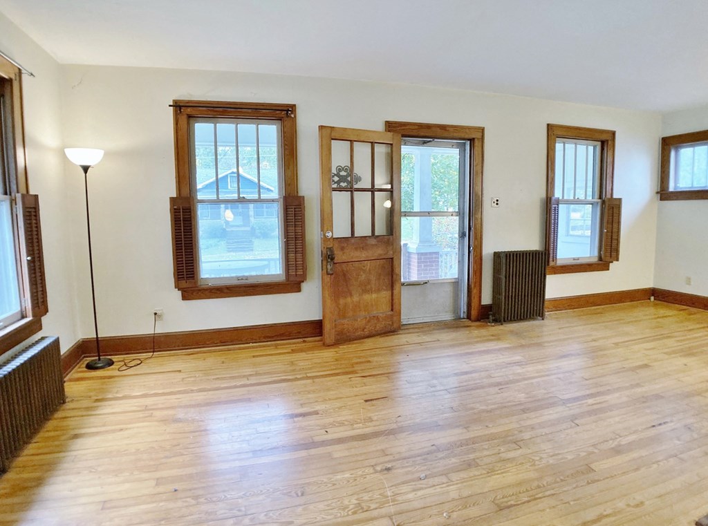an empty living room with wooden floors and windows