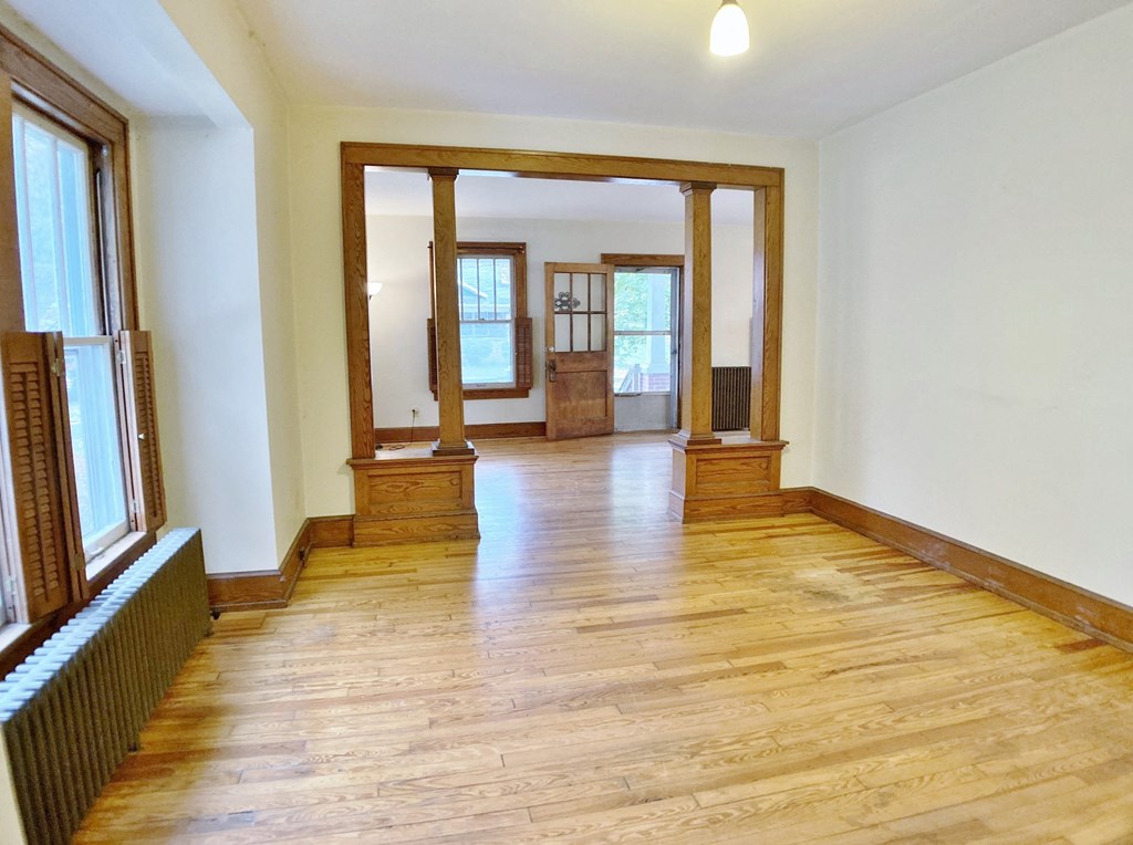 an empty living room with wood floors and a window