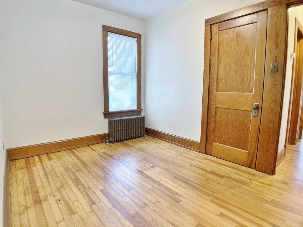 an empty living room with wood floors and a wooden door