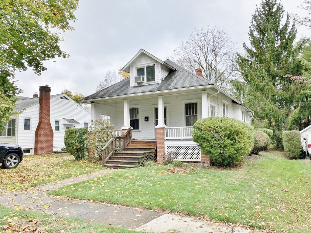 a white house with a porch and a car in front of it
