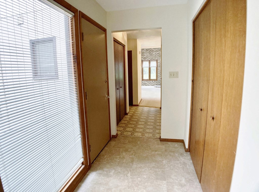 the hallway of a house with a door to a hallway of closets