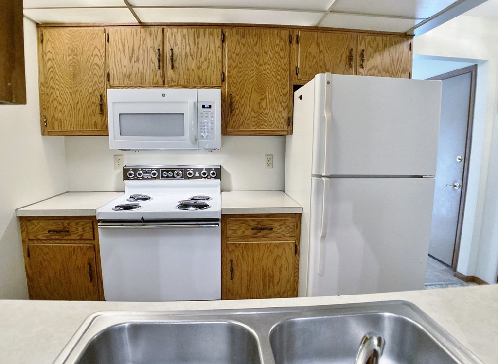 an empty kitchen with white appliances and wooden cabinets