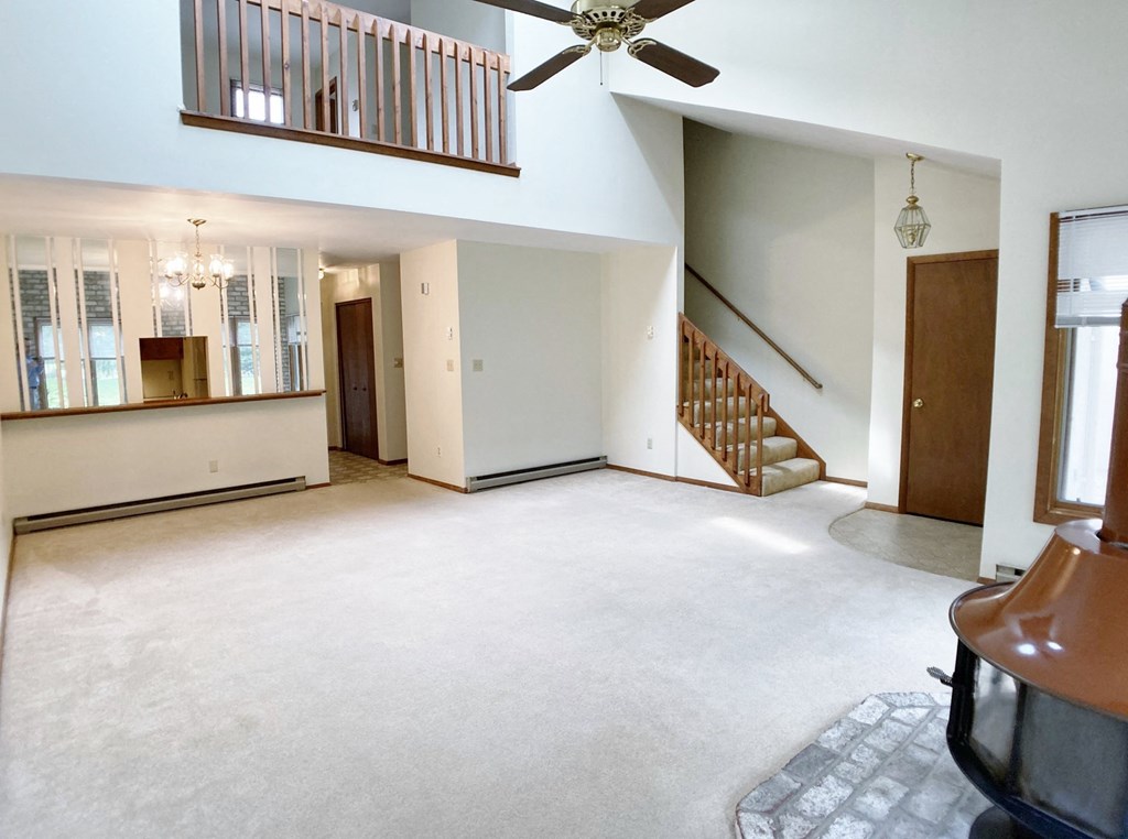 an empty living room with a ceiling fan and a staircase