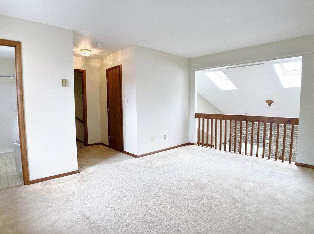 an empty living room with a railing and a window