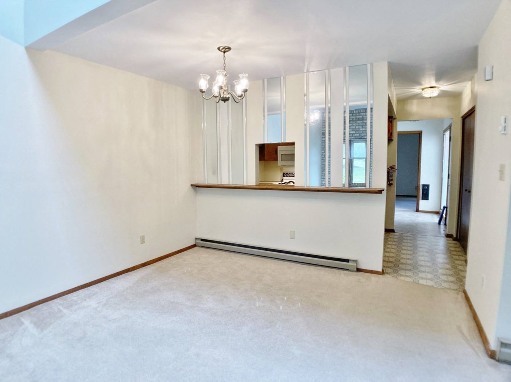 an empty living room and kitchen with a counter and a chandelier