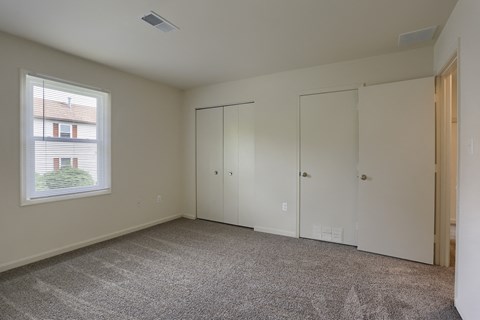 a bedroom with carpet and white walls and a window