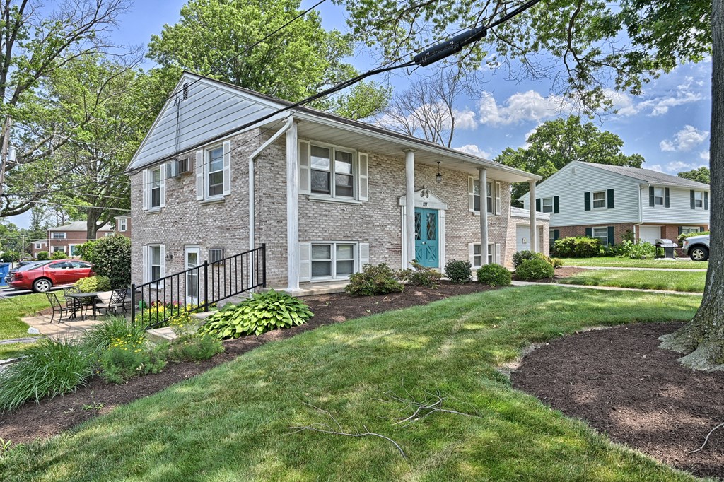 the front of a brick house with a lawn and trees