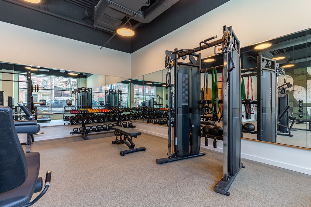 A gym with a variety of equipment including a squat rack, bench press, and a mirror.