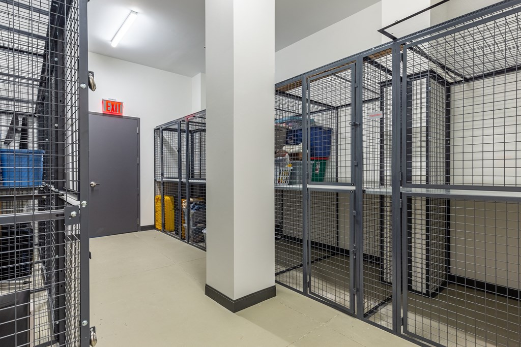 A long hallway with a metal gate on the left and a red exit sign above it.