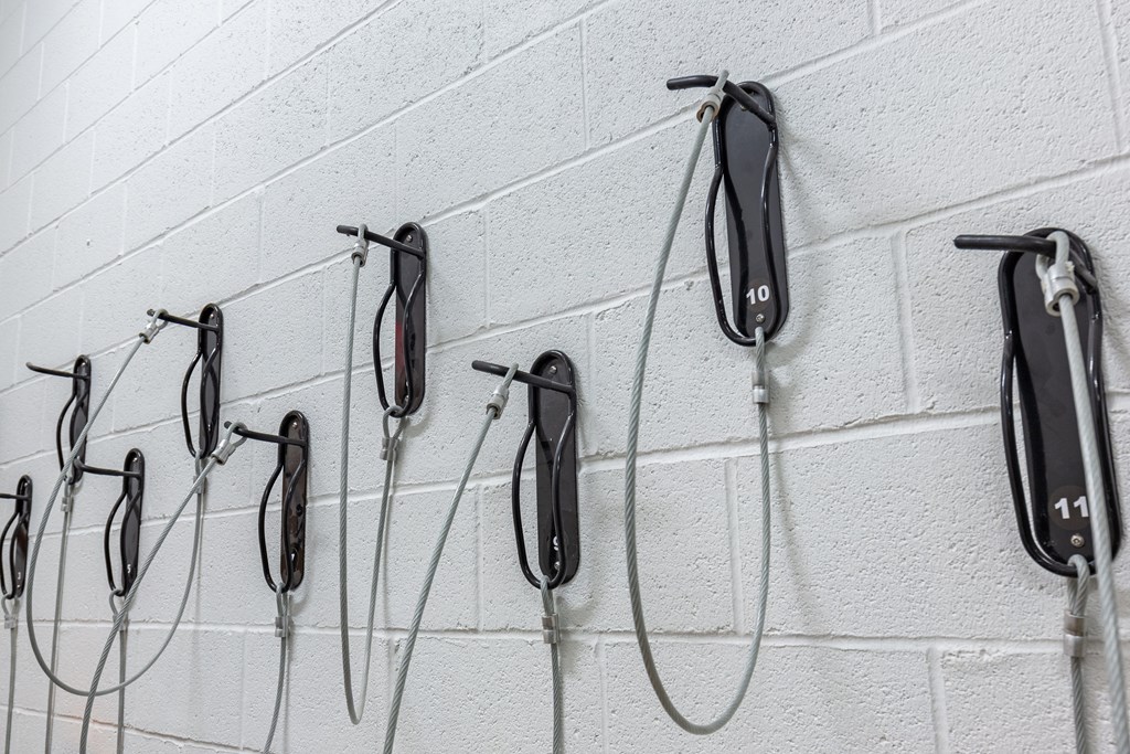 A wall of white brick with multiple black and silver hand dryers attached to it.