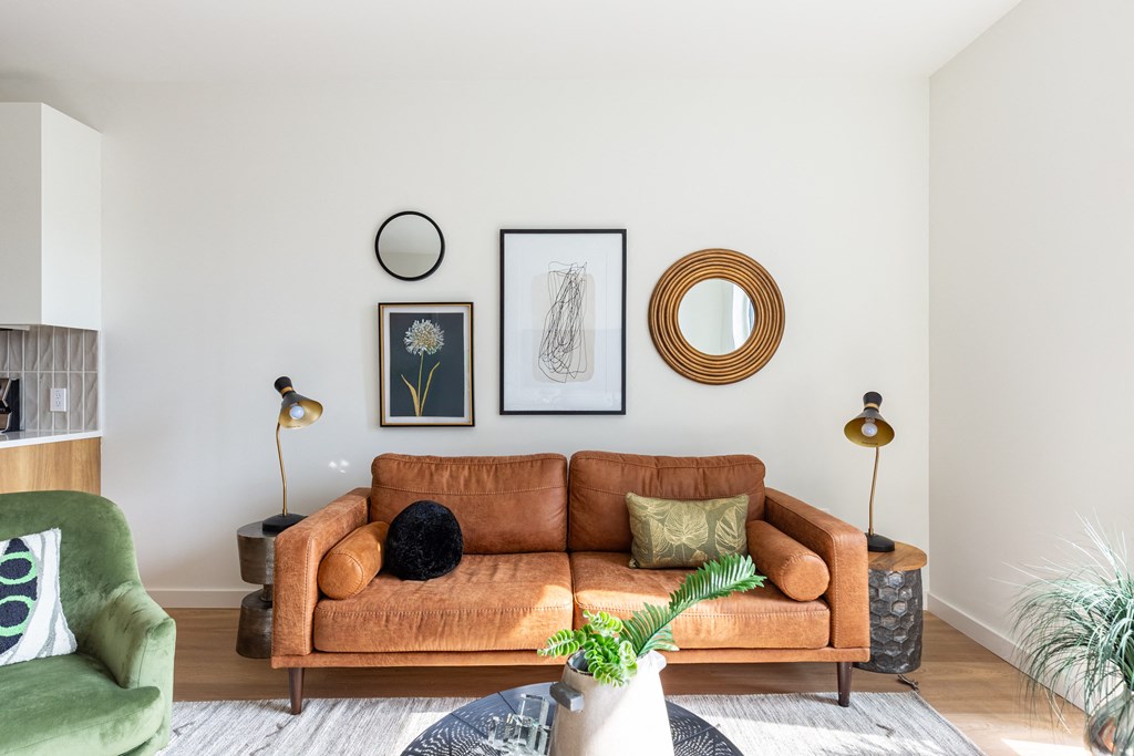 A living room with a brown couch, green chair, and a plant.