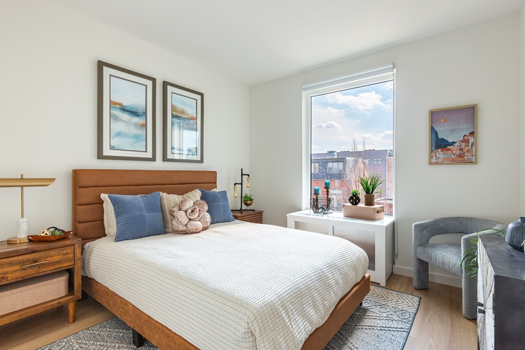 A bedroom with a large bed, a nightstand, and a chair.