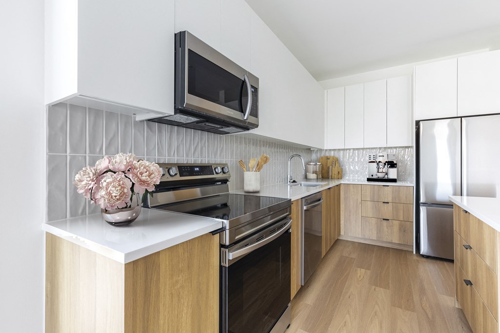 A modern kitchen with wooden cabinets and a black microwave above the stove.