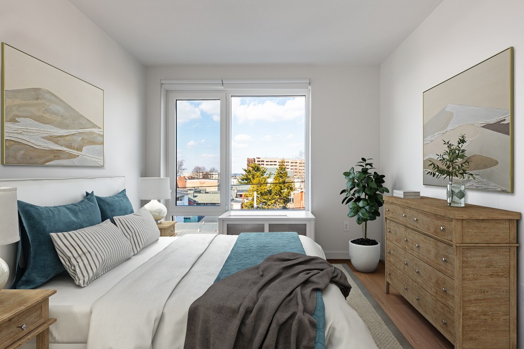 A bedroom with a large bed, a window with a view of the city, and a wooden dresser.