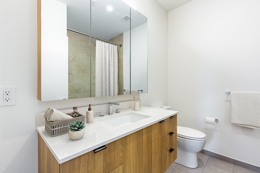 A bathroom with a white counter top and a white toilet.