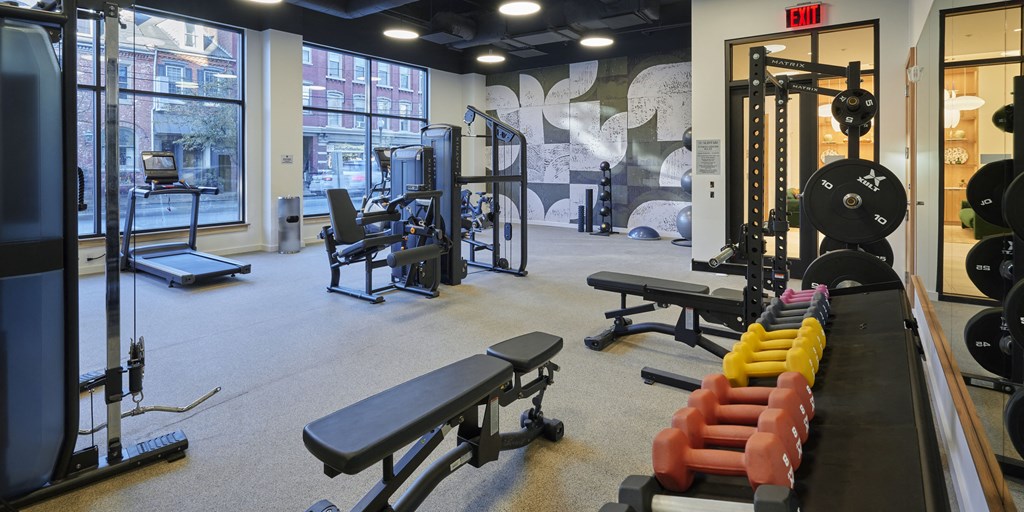 a fitness room with weights and cardio equipment and a large window
