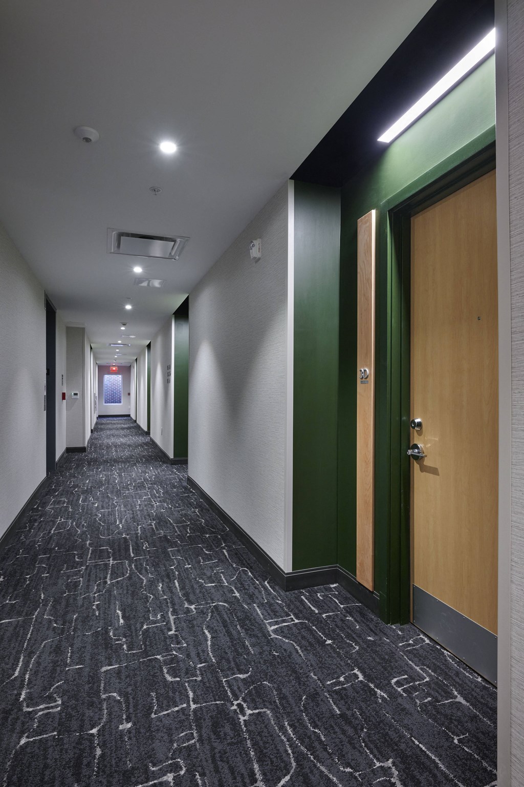 a long corridor with wooden doors and white walls