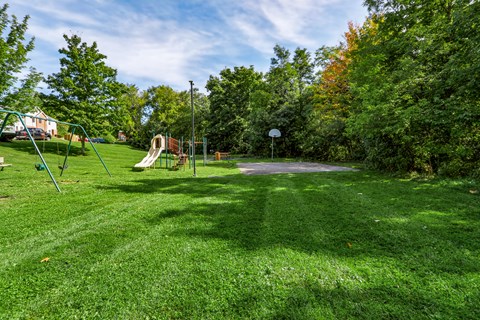 A playground with a slide, swings, and a basketball hoop.