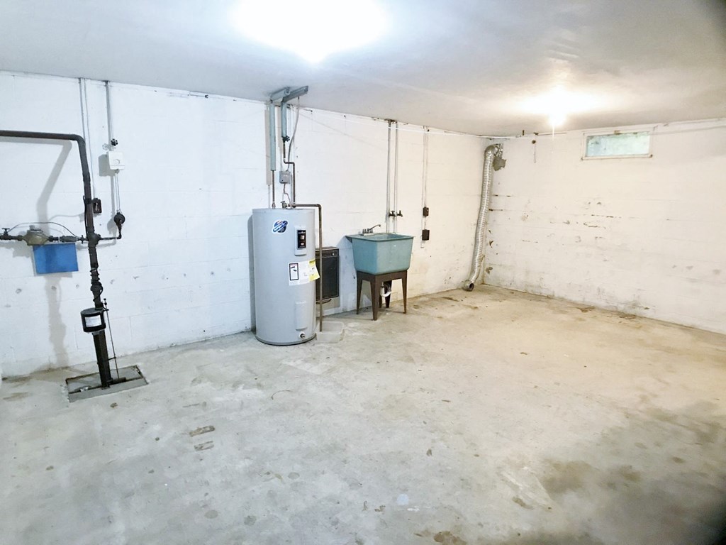 the inside of a garage with a water heater and a sink
