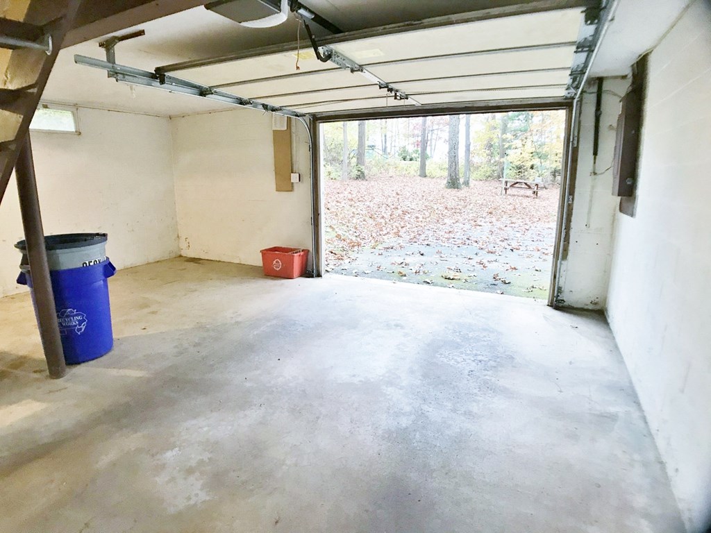 a garage with a concrete floor and a blue trash can