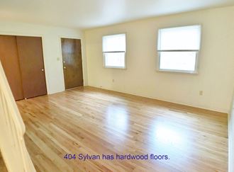 a room with a hardwood floor and a door and two windows